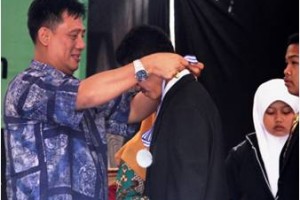 ketua Yayasan ITUS mengalungkan medali kepada siswa kelas IX SMP ITUS Kuningan